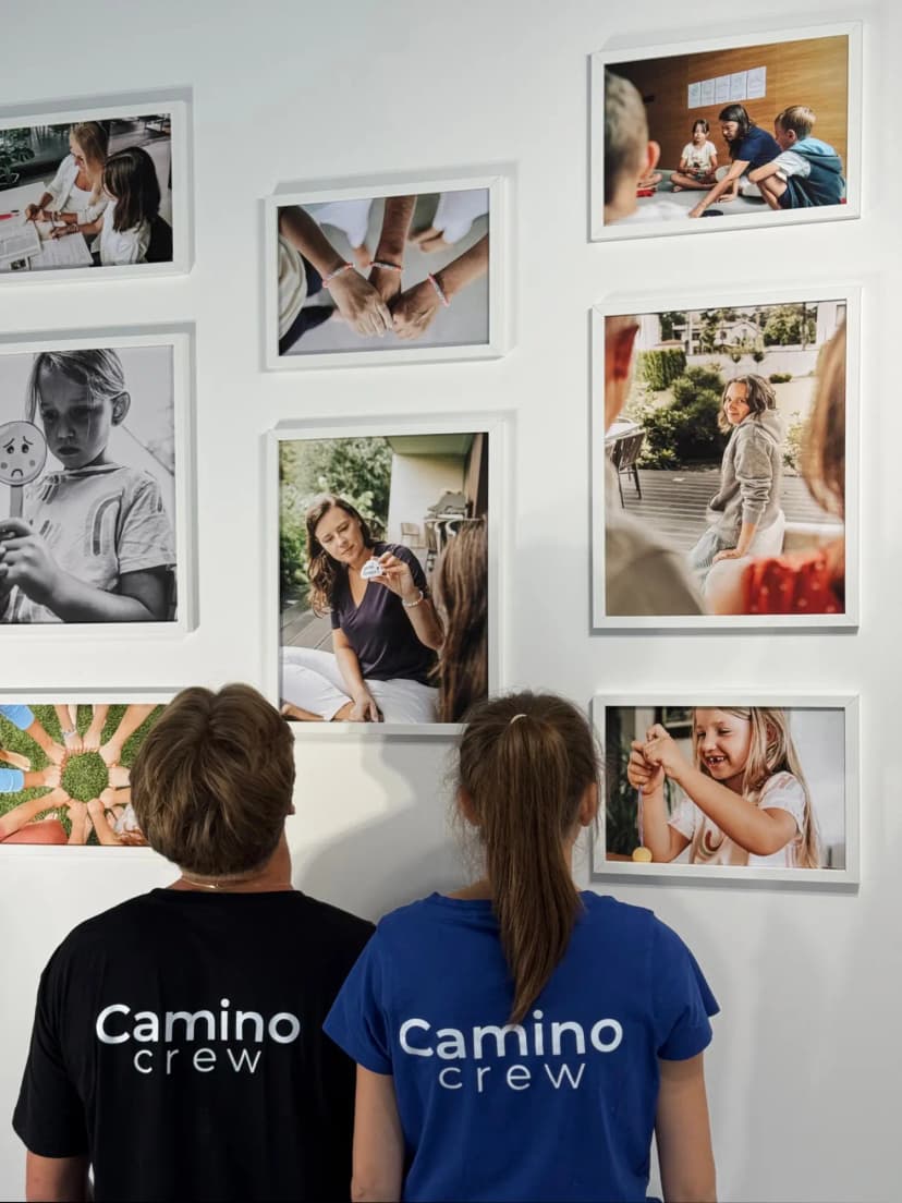 El personal de Camino con camisetas a juego mirando su nueva pared de la galería con múltiples marcos para fotos